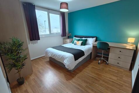 Bright bedroom with desk, storage and teal feat...