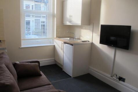 Compact studio lounge with kitchenette and TV...