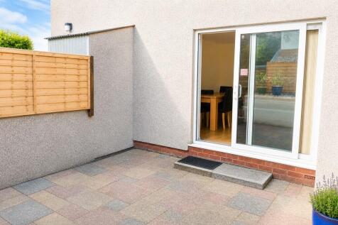 Sunny paved patio with sliding door access...