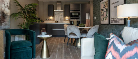 Modern kitchen and living area with dark grey cabinets, cream seating, and colourful cushions in a s