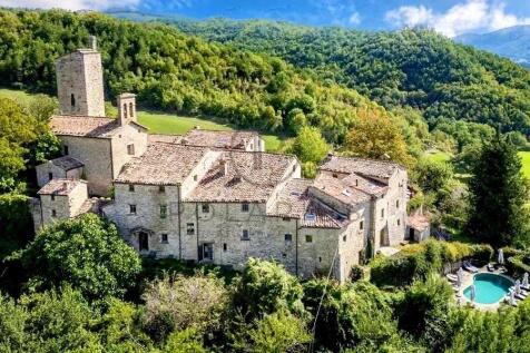 Stone buildings nestled in a lush hillside landsca