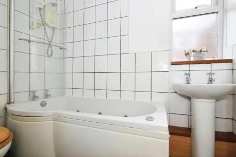 Bright tiled bathroom with a corner bath and ov...