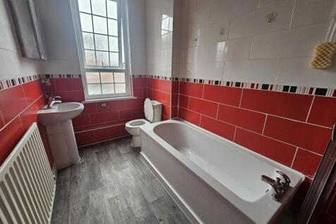 Bright, modern bathroom with a white bathtub, p...