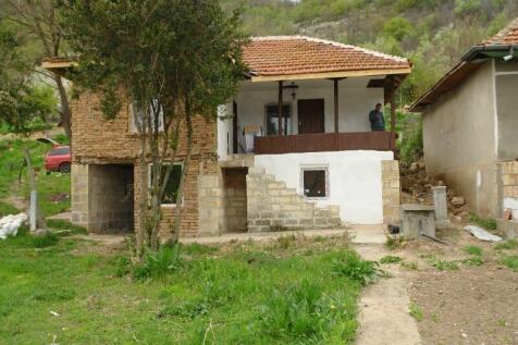 Front view of two-storey rural Bulgarian house with stone and brick walls and tiled roof