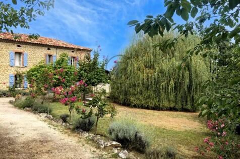 A charming stone house with blue shutters is surro
