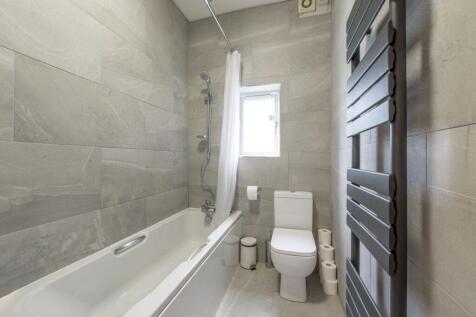 Modern bathroom with sleek grey tiling and bath...