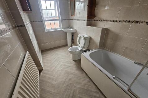 Bright, modern bathroom with tiled walls, a bat...