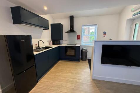 Modern L-shaped kitchen with dark cabinetry, in...