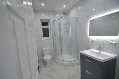 Modern tiled bathroom with a corner glass showe...