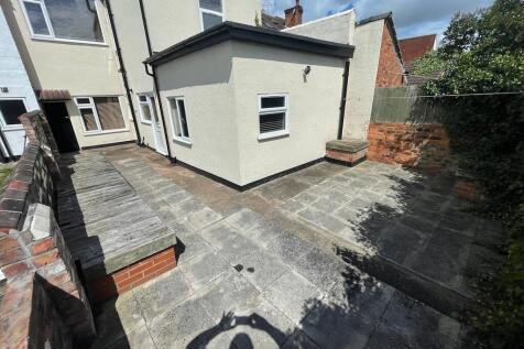 Private paved courtyard with low brick walls, a...