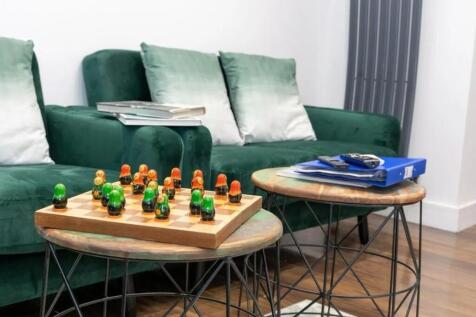 Bright, modern living area with a plush green s...