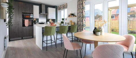 Modern kitchen and dining area with colourful chairs, large windows, and a garden view, decorated in