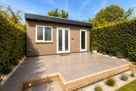 Spacious paved patio with modern garden buildin...