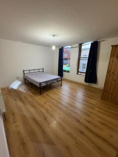 Spacious master bedroom with sleek wood floorin...