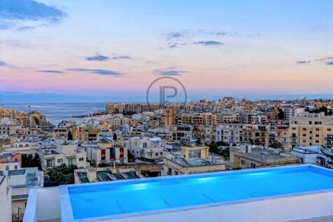 Rooftop pool overlooking a cityscape at sunset, wi