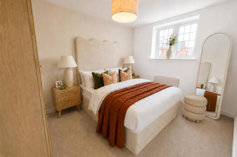A cozy bedroom features a bed with a rust-colored throw in the foreground