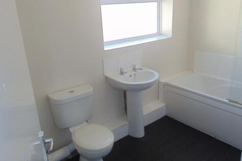 Bright and clean bathroom suite featuring a whi...