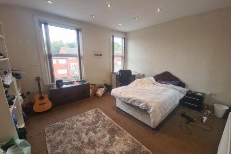 A spacious master bedroom well-lit by large win...