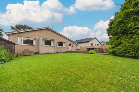 A generous lawned garden with mature planted borders and patio seating areas