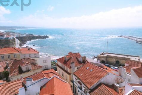 A coastal town with red-tiled rooftops overlooks a