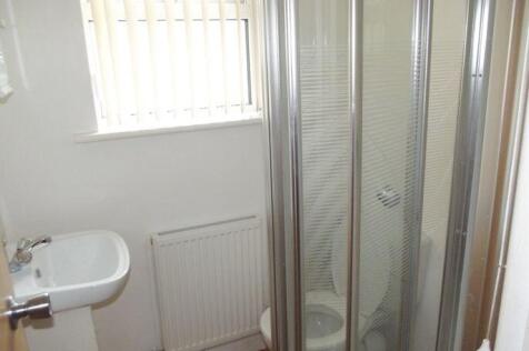 Compact, clean bathroom with a corner shower cu...