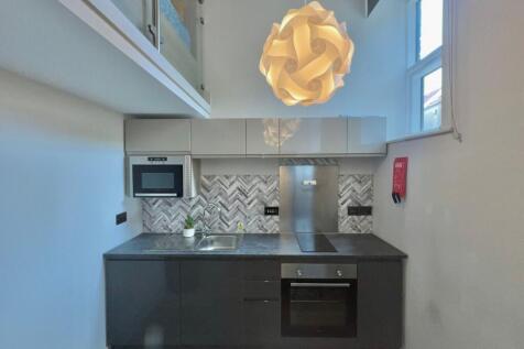 Modern compact kitchen with sleek dark lower ca...