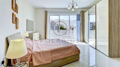 A bright bedroom with a double bed, pink bedding, 