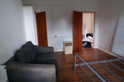 A modest living room with a dark sofa, wooden f...