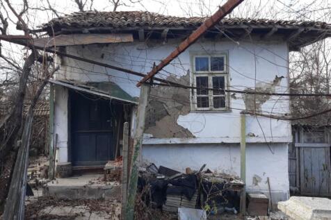 Close-up of the front entrance of a traditional Bulgarian house showing peeling plaster and a dark blue door