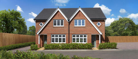 Two modern semi-detached red brick houses with gabled roofs, white-framed windows, and front hedges