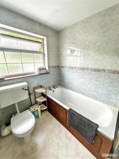Bright bathroom with a full-sized tub and windo...