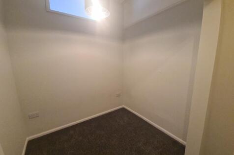 Small neutral room with high window and carpet...