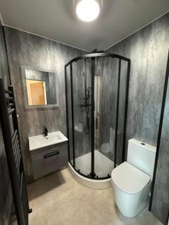 Modern en-suite bathroom with a curved glass sh...