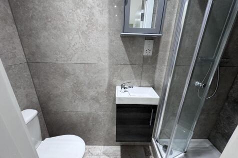 Modern tiled bathroom with a corner glass showe...