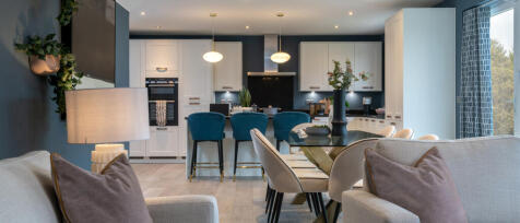 Contemporary open-plan kitchen and living area with coloured walls, white cabinets, and modern furni