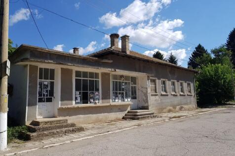 Side perspective of the bakery building showing entrance doors and windows with posted notices