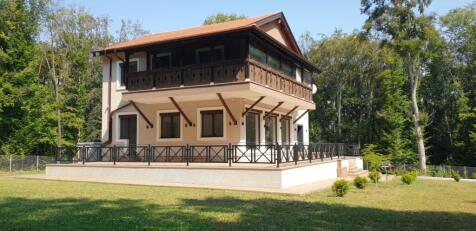 Two-storey house with large balcony and terrace surrounded by trees