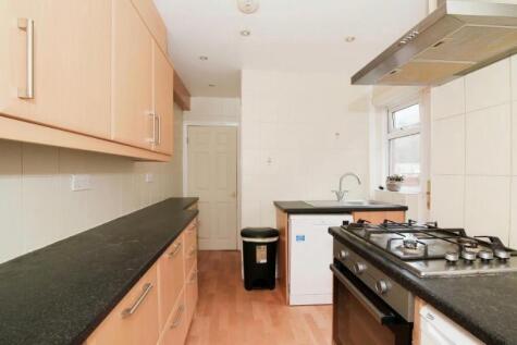 Bright galley-style kitchen with light wood cab...
