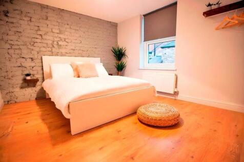 Bright modern bedroom with exposed brick featur...