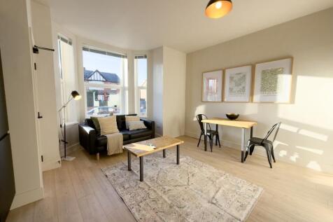 Sun-drenched living area with chic wood floorin...