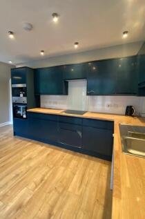 Modern kitchen featuring sleek, dark blue cabin...