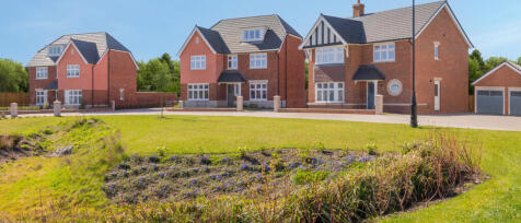 Modern brick and pink houses with large windows and landscaped gardens under a clear blue sky at Blo
