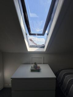 Bright bedroom with large skylight and blue sky...