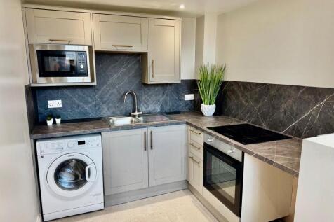 Modern kitchen with stone worktops and applianc...
