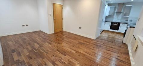 Bright open-plan living area with warm wood flo...