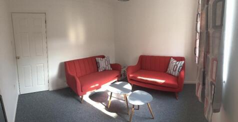 Bright, tidy living room with matching red two-...
