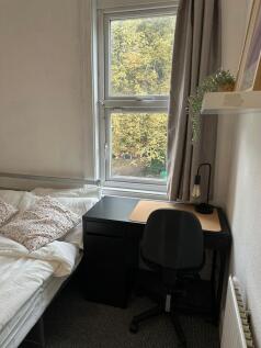 A cozy single bedroom featuring a comfortable b...