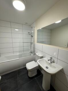 Bright, modern bathroom with a white bathtub an...