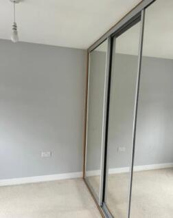 Bright neutral bedroom corner with fitted slidi...
