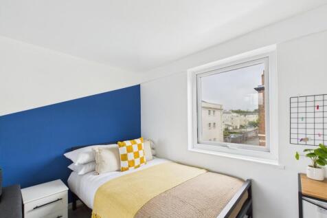 Bright, neatly styled bedroom with a comfortabl...